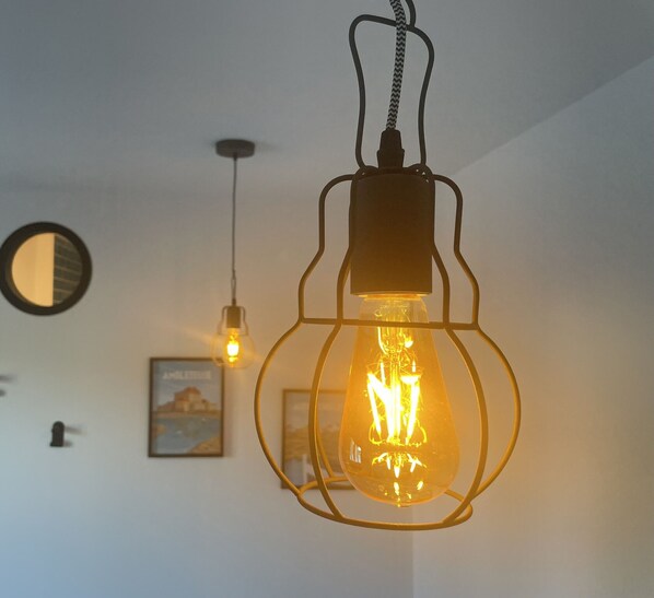 A room with a hanging light fixture and a wall-mounted mirror.