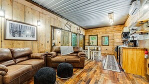 Un intérieur de chalet chaleureux avec des murs en bois, un coin repas et une petite cuisine.