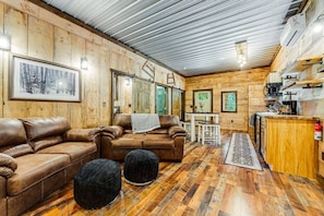 Interior acogedor de una cabaña con paredes de madera, un comedor y una kitchenette.