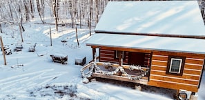 Een houten hutje met een veranda, omringd door met sneeuw bedekte bomen.