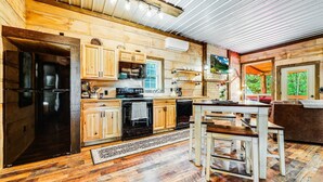 Une cuisine rustique avec des meubles en bois, un réfrigérateur noir et un coin repas équipé d’une banquette.