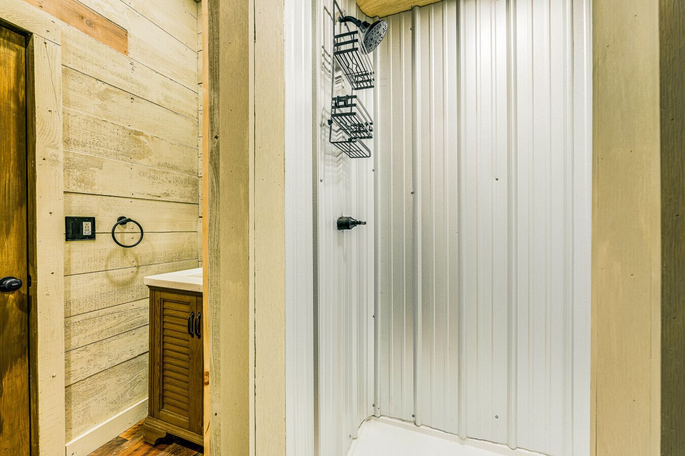 Un baño con tocador de madera, inodoro y puerta blanca con barra para toallas.