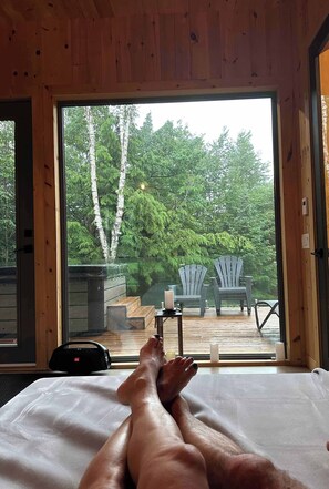 Un dormitorio con un ventanal grande que da a una terraza con sillas Adirondack y una mesa de madera.