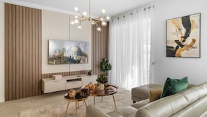 Un salon moderne doté d’un grand téléviseur à écran plat, d’un canapé, d’une table basse et d’un lustre.