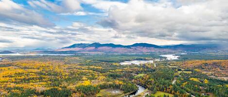 A panoramic view of a valley with autumn foliage, a river, and distant mountains.