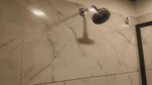 A bathroom with a shower head mounted on a marble wall. - Wishotel Xpress Hotel GK Inn  (Dewas)