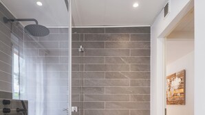 Un bagno moderno con doccia vetro, un water e un lavandino.