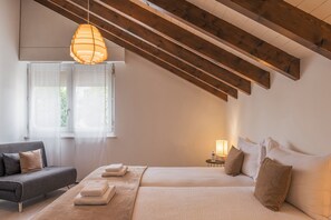 Une chambre à coucher comprenant un lit, un canapé, une table de chevet avec une lampe et un luminaire suspendu.