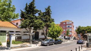 Une rue avec un arrêt de bus, des voitures garées et des immeubles aux façades rouges et blanches.