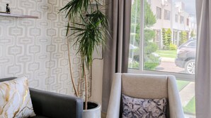 A modern living room with a sofa, armchair, potted plant, and a large window with curtains. - Bright Home With Pool Near Valquirico (Huejotzingo)