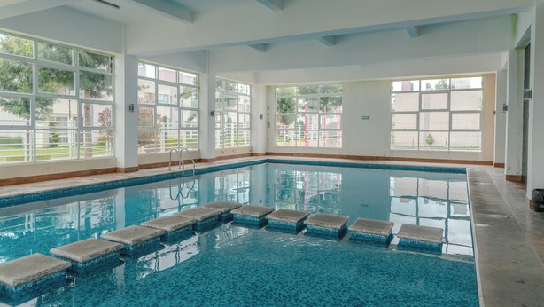 An indoor swimming pool with clear blue water, large windows, and a tiled floor. - Bright Home With Pool Near Valquirico (Huejotzingo)