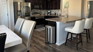 Una cocina moderna con armarios de madera oscura, electrodomésticos de acero inoxidable y una isla central con taburetes de bar.