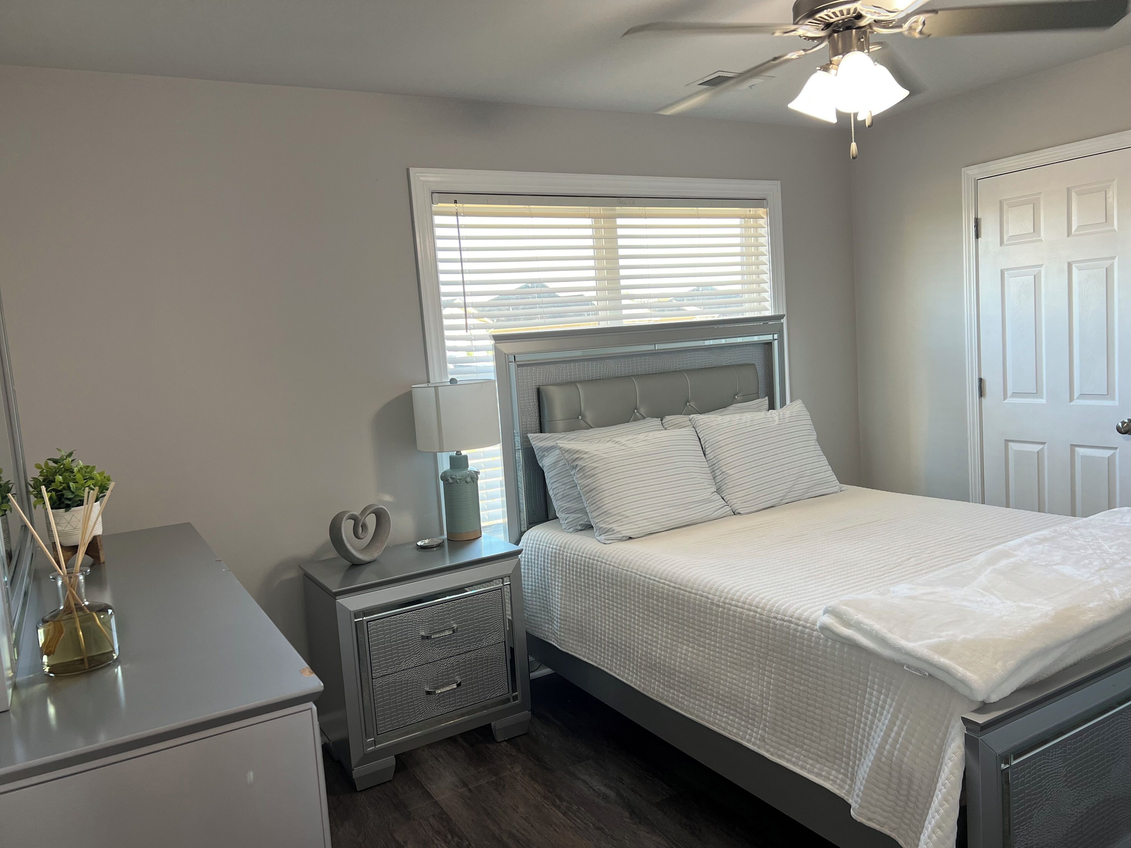 Une chambre à coucher avec un lit, une table de chevet, une lampe et un ventilateur de plafond.
