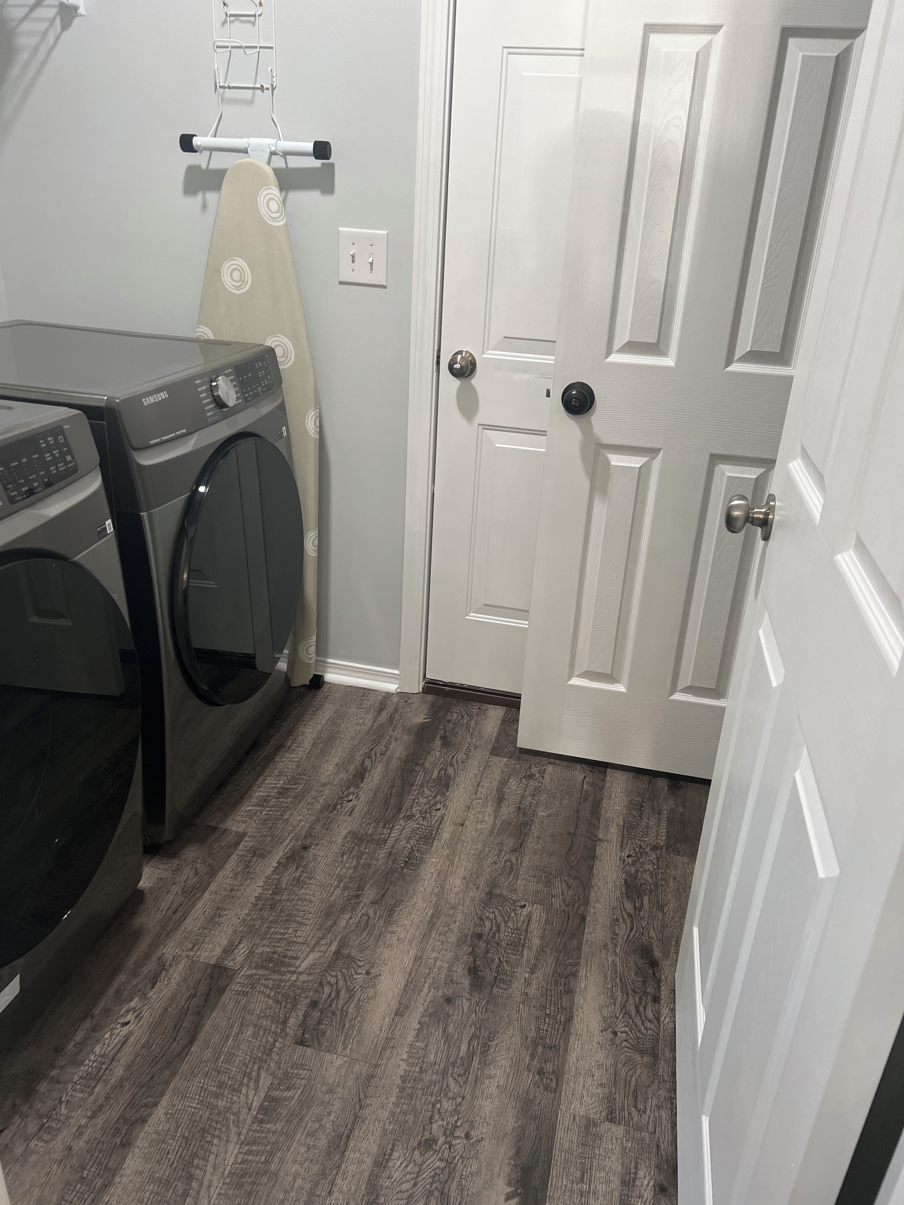 Un lavadero con lavadora, secadora y una puerta que da a otra habitación.