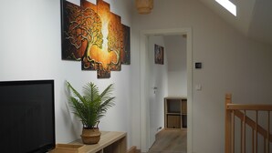 A modern living room with a flat-screen TV, a potted plant, and artwork on the wall.