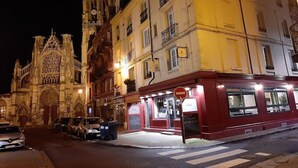 A historic cathedral with intricate Gothic architecture, adjacent to a brightly lit red building with a visible storefront. - Hôtel Au Grand Duquesne  (Dieppe)