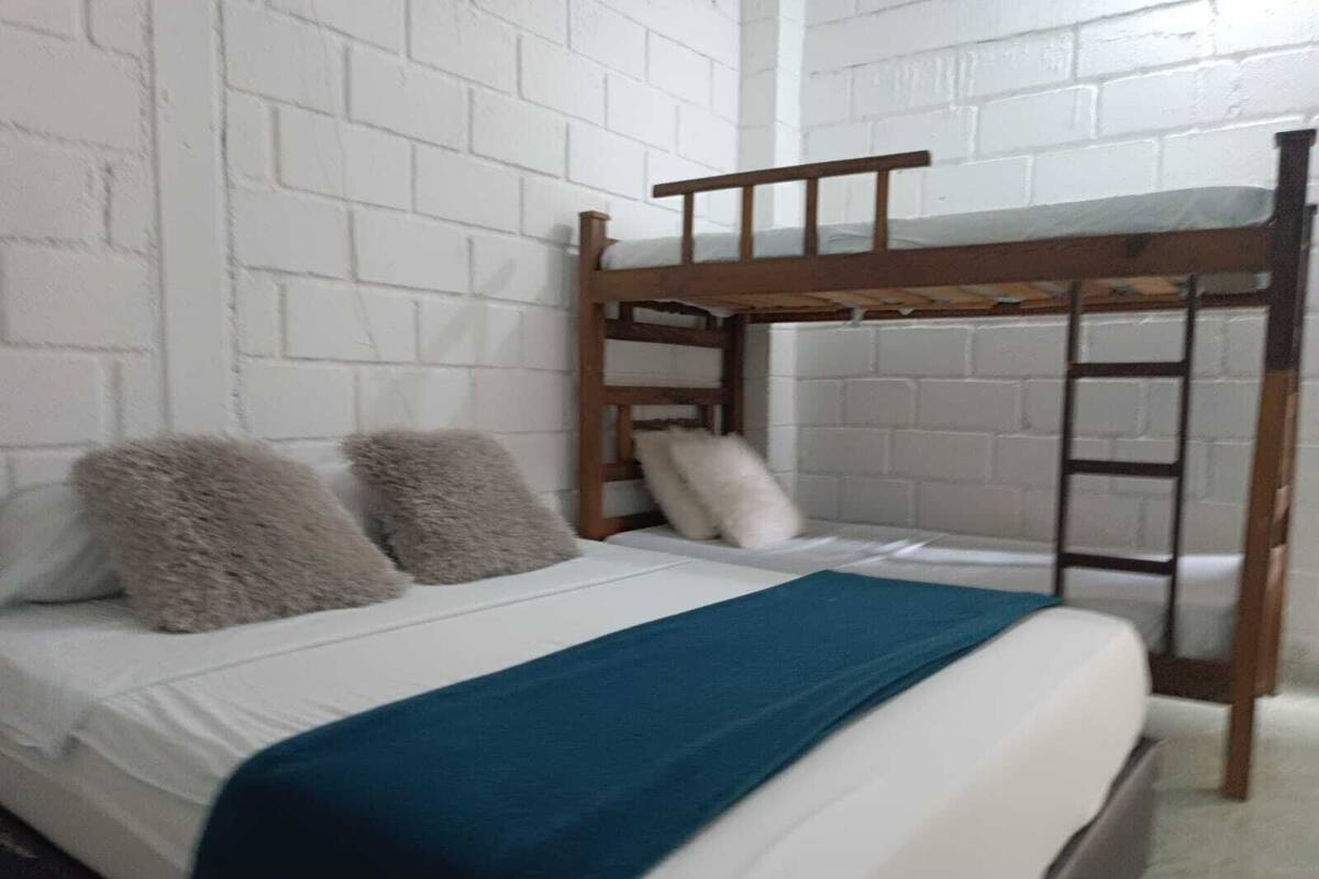 Una cama litera con estructura de madera y ropa de cama blanca.
