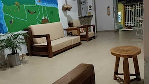 A living room with a sofa, chairs, a wooden stool, and a mural on the wall. - Taganga Tropical House (Santa Marta)