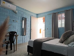 Une pièce avec un lit, une chaise, un miroir et une fenêtre.