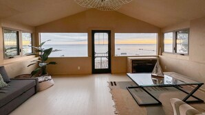 A spacious living room with a view of the sea, a large ceiling light, and a cozy seating area.
