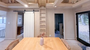 A spacious room with a large wooden table, a sliding door, and a view through a large window.