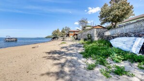 A beachside property with a stone wall, a wooden deck, and a view of the sea. - Charming 3-bedroom lakefront house with large yard and sandy beach (Colchester)