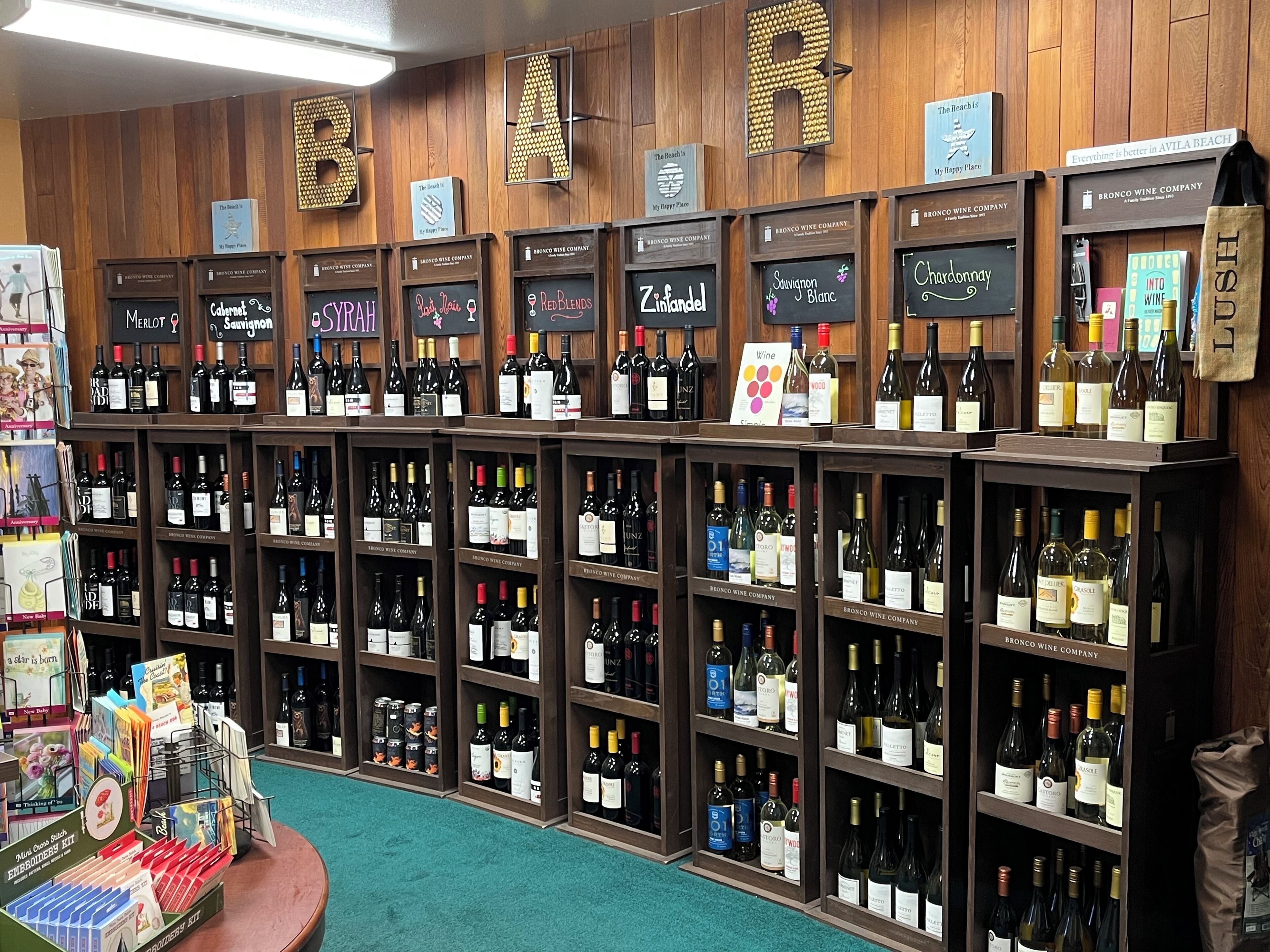 A wine store with wooden shelves and signs indicating different wine brands and types.