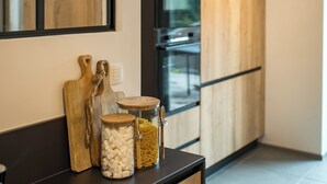 A modern kitchen with wooden cabinets, a built-in oven, and two jars on a black countertop.