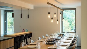 A modern dining area with a long wooden table set for a meal, surrounded by upholstered chairs with wooden legs.