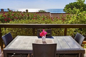 A patio with a table and chairs, a vase of flowers, and a view of the sea. - Porto Corallo Two-room apartment 4 beds (Villaputzu)