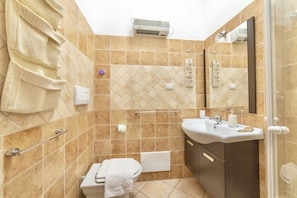 A bathroom with a toilet, sink, and shower area.