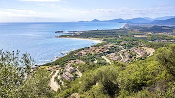 Un village côtier avec des maisons à étages, une plage et un paysage montagneux en arrière-plan.