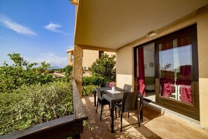 Un balcon avec une table et des chaises, une vue sur la verdure et un bâtiment en arrière-plan.