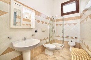 Une salle de bain équipée d’un lavabo, de toilettes, d’un bidet et d’une douche à parois de verre.