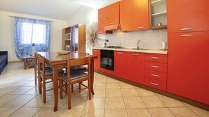 A modern kitchen with red cabinets, a dining table with chairs, and a large decorative mirror.