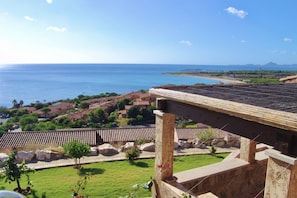 Une vue sur la côte, avec un bâtiment doté d’une pergola et de colonnes en pierre, surplombant un quartier résidentiel et la mer.