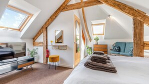 A bedroom with a sloped ceiling, a bed, a TV, a desk, and a sofa. - Roosters Rest - UK48255 (Downderry)