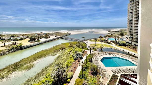 Un complejo turístico costero con piscina, playa y vista al océano.