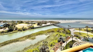 Un complejo turístico frente al mar con un puerto deportivo, playa de arena y una vía fluvial sinuosa.