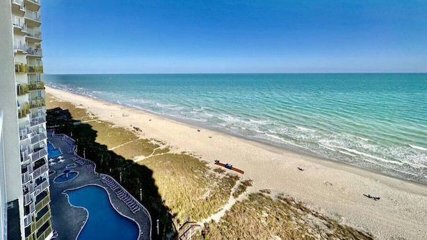 Un hotel frente a la playa con piscina, playa y vistas al océano.