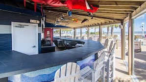 Zona de bar techada al aire libre con mesa de billar, asientos y vistas a la playa.