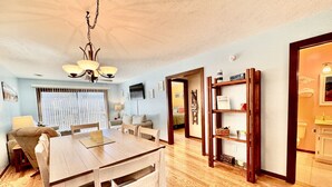 Un amplio salón con una mesa de comedor de madera, un sofá y una estantería.
