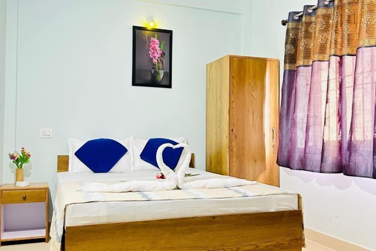 A neatly made bed with a blue headboard, a wooden wardrobe, and a framed picture on the wall.