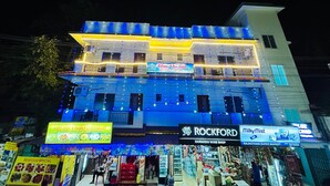 A multi-story building with illuminated signage for a restaurant, a wine shop, and a market. - Blue Stay Inn Holiday Home - Near Baga Calangute Beach (Calangute)