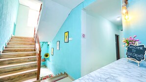 A staircase with wooden steps leading to a landing with a marble reception desk. - Blue Stay Inn Holiday Home - Near Baga Calangute Beach (Calangute)
