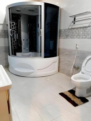 A modern bathroom with a corner shower enclosure, a toilet, and a sink. - Ahlin Suites 3 (Riyadh)