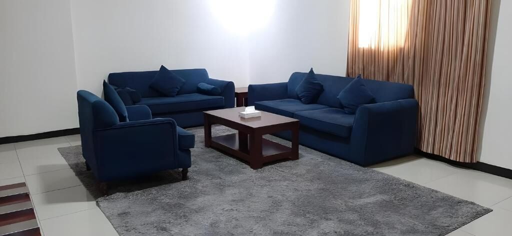 A living room with two blue sofas, a small wooden coffee table, and a grey rug.
