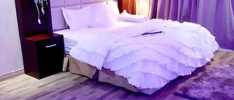 Un dormitorio con una cama grande, una mesita de noche, un tocador y un aire acondicionado instalado en la pared.
