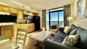 A compact living space with a kitchen, dining area, and a balcony with a view. - Tropical Resort 1BR 1407 (North Myrtle Beach)