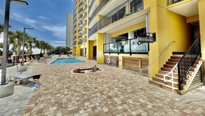 A hotel with a pool area, outdoor seating, and a sign for restrooms.